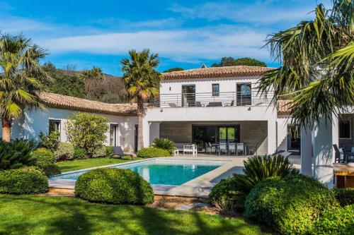 une maison avec une piscine et des palmiers dans l'établissement Villa d'Exception Golfe de Saint-Tropez, au Plan-de-la-Tour