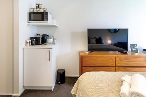 a bedroom with a bed and a tv on a dresser at Serene Studio Escape on Madras in Christchurch