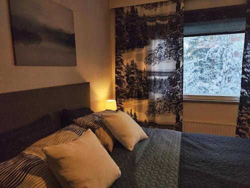 Un dormitorio con una cama con dos almohadas y una ventana. en Spacious apartment with balcony and free WiFi, en Rovaniemi