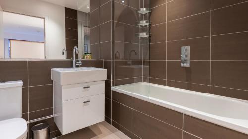 a bathroom with a sink and a tub and a toilet at Barbican Serviced Apartments by LovelyStay in London