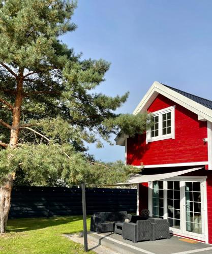 a red house with a tree in front of it at Czerwone Domki in Dębki