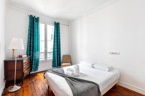 une chambre avec un lit et une fenêtre avec des rideaux bleus dans l'établissement GuestReady- Modern Comfort near Parc Monceau for 6, à Paris