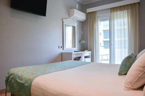 a bedroom with a bed and a desk and a window at Hotel Costasol in Almería