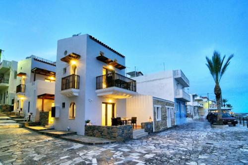 a white house with a palm tree on a street at Myrtos Mare Suite Mit Meerblick in Myrtos