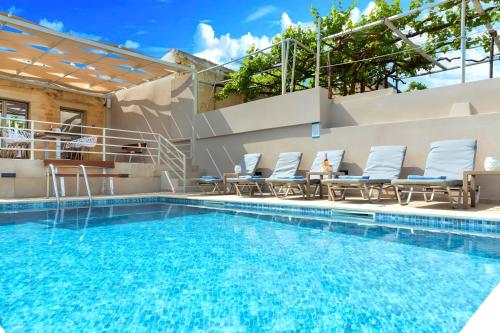 a pool with chaise lounge chairs and a swimming pool at Cretan Breeze Villa Beheizter Privater Swimmingpool in Dhrámia