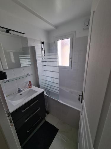 une salle de bain blanche avec un lavabo et un miroir dans l'établissement Socoa- 2 chambres- Proche Plage, à Urrugne