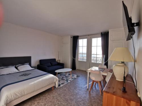 une chambre avec un lit, un bureau et un canapé dans l'établissement Grand studio face à la mer, à Houlgate