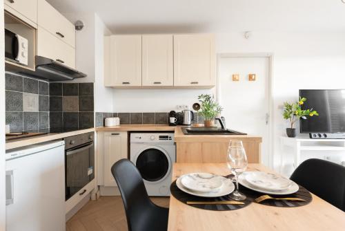 une cuisine avec une table et des chaises et une cuisine avec des armoires blanches dans l'établissement Joli T2 avec terrasse et Parking, à Toulouse