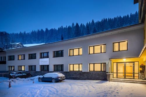 a building with a car parked in a parking lot at Residence Riverside in Pec pod Sněžkou