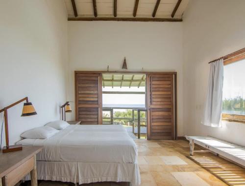 ein Schlafzimmer mit einem Bett und einem großen Fenster in der Unterkunft Tudo Bom Kitesurf Dream Villa in Taíba