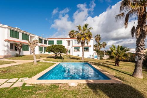 a house with a swimming pool and palm trees at Menorca Apartamento ALOHA by Mauter Villas in Cala en Blanes