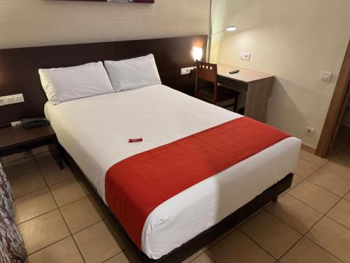 a large bed in a hotel room with a desk at Hotel Canal Olímpic in Castelldefels