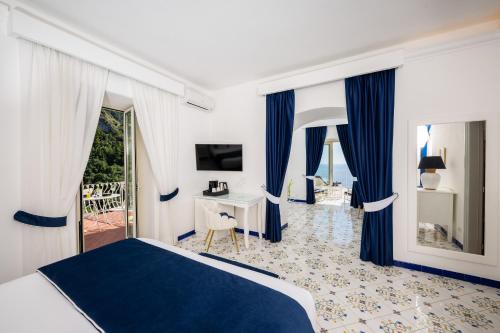 a bedroom with a bed and a desk and a television at Grand Hotel Tritone in Praiano