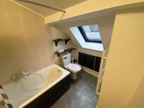 une salle de bain avec baignoire et toilettes et une fenêtre dans l'établissement Cosy près de la Gare - 366, à Rouen