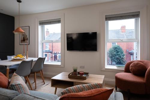 a living room with a couch and a table and two windows at Brayford House Burton Road - stylish accommodation suitable for families and contractors in Lincoln