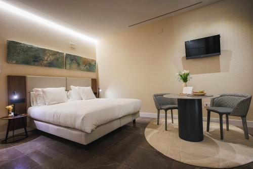 a hotel room with a bed and a table and a tv at Corral del Carbón GG Luxury Hotel Boutique in Granada