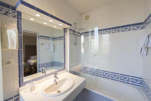 a bathroom with a sink and a tub and a mirror at Hôtel Bristol in Le Touquet-Paris-Plage