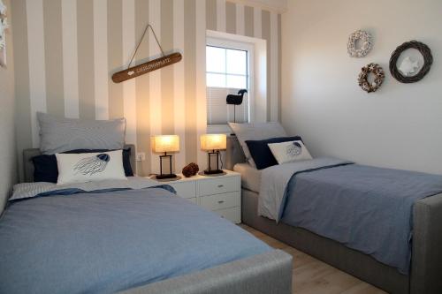a bedroom with two beds and two lamps and a window at Sielentium in Greetsiel