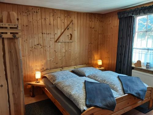 Un dormitorio con paredes de madera y una cama con sábanas azules. en Fewo Holzwurm, en Braunlage