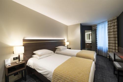 a hotel room with two beds and two lamps at Hôtel Bristol in Le Touquet-Paris-Plage