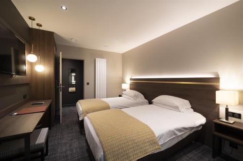 a hotel room with two beds and a desk at Hôtel Bristol in Le Touquet-Paris-Plage