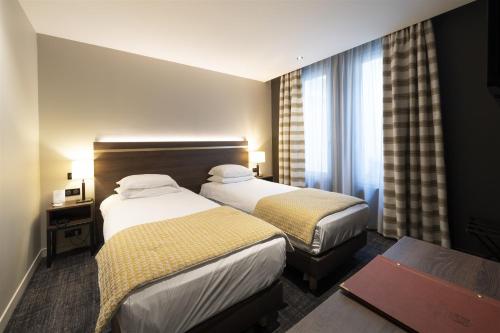 a hotel room with two beds and a table at Hôtel Bristol in Le Touquet-Paris-Plage