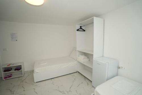 a white bathroom with a toilet and a sink at Enles Hotel in Durrës