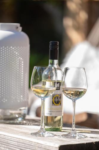 a bottle of white wine next to two wine glasses at Design Hotel ALPENLIEBE - - - - Boutique-Flair - - - - in Inzell