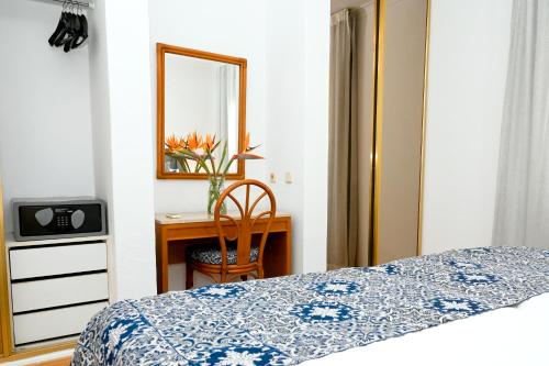 a bedroom with a bed and a desk with a mirror at Muthu Clube Praia da Oura in Albufeira