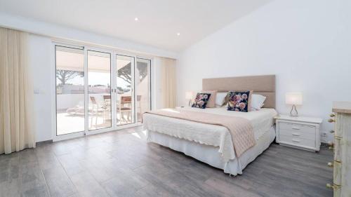 a white bedroom with a bed and a balcony at Villa Florida in Almancil