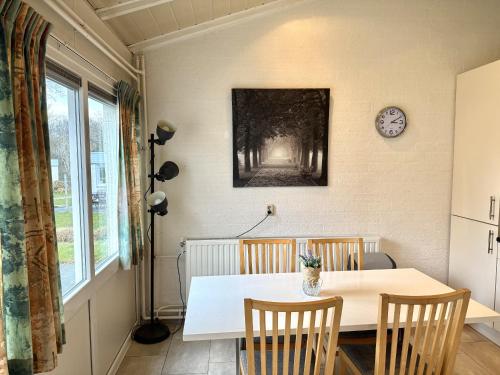a dining room table with two chairs and a clock on the wall at Bungalowpark Simpelveld - Schakel 6 in Simpelveld