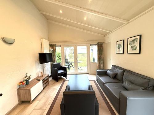 a living room with a couch and a tv at Bungalowpark Simpelveld - Schakel 6 in Simpelveld