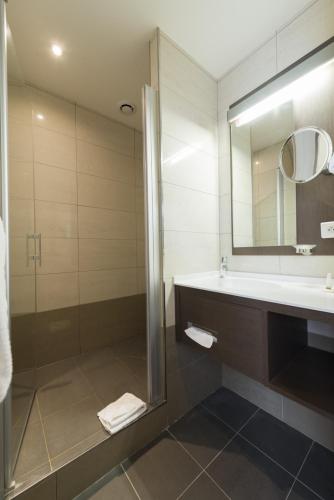 a bathroom with a shower and a sink and a mirror at Hôtel Bristol in Le Touquet-Paris-Plage