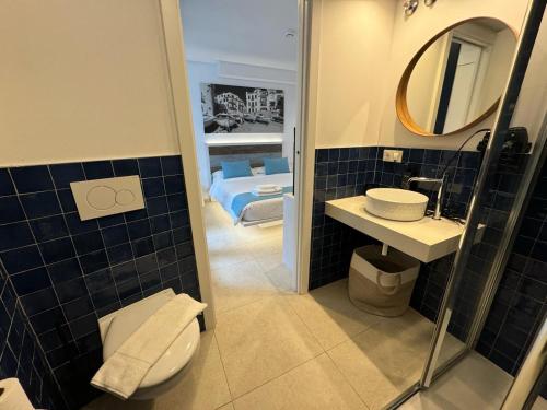a bathroom with a toilet and a sink and a bed at Hotel Boutique Es Blau in Cadaqués