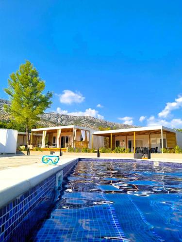 a swimming pool in front of a house at Mobile Home Blue Charm Camping Dalmata Orebić in Orebić