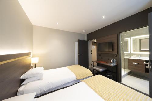 a hotel room with two beds and a desk at Hôtel Bristol in Le Touquet-Paris-Plage