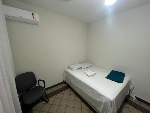 a small room with a bed and a chair at Ar split, internet, cozinha e banheiro privativo in Goiânia