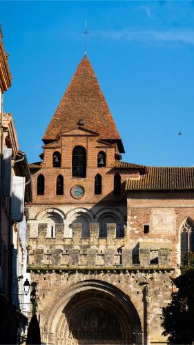 a building with a tower with a clock on it at Hôtel & Spa Le Moulin de Moissac in Moissac
