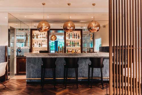 a bar in a restaurant with black stools at Seehotel Dr. Jilly in Pörtschach am Wörthersee