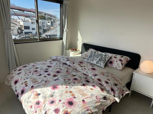a bedroom with a bed with a floral comforter and a window at Mark的足立江北站民宿 in Tokyo