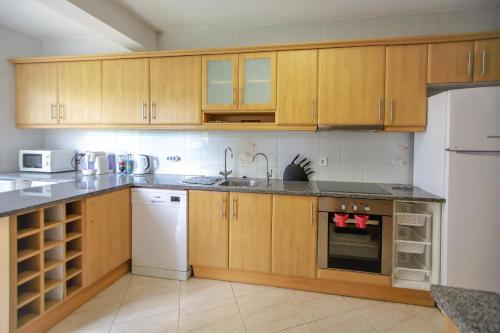a kitchen with wooden cabinets and white appliances at Vila Ventura Marina in Albufeira
