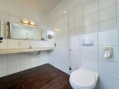 a bathroom with a toilet and a sink and a mirror at Hotel Weisse Düne in Borkum