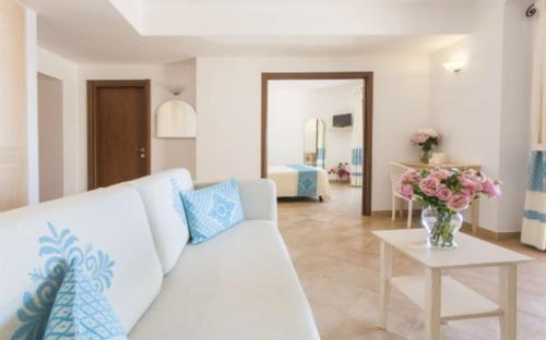 a living room with a white couch and a table with flowers at Hotel Dei Pini in Alghero