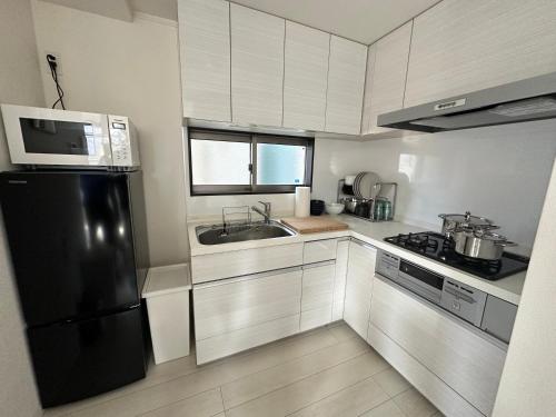 a kitchen with a black refrigerator and a sink at Mark的足立江北站民宿 in Tokyo