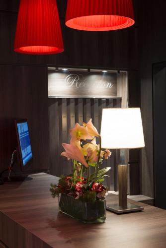 a vase of flowers on a desk with a lamp at Hôtel Bristol in Le Touquet-Paris-Plage
