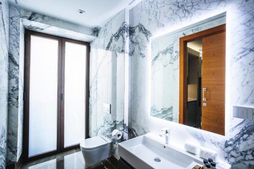 a white bathroom with a sink and a mirror at Corral del Carbón GG Luxury Hotel Boutique in Granada