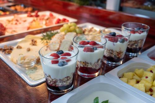 a table topped with glasses of yogurt and berries at Design Hotel ALPENLIEBE - - - - Boutique-Flair - - - - in Inzell
