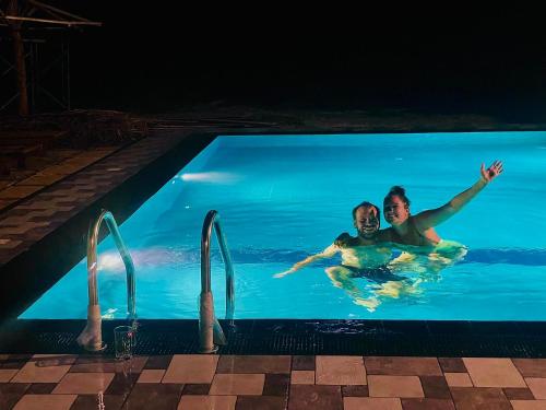 two people swimming in a swimming pool at night at Dhanaya Safari Home in Udawalawe