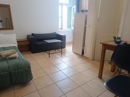 a living room with a couch a table and a refrigerator at Friendly Studio The bed is semi double in Mytilini
