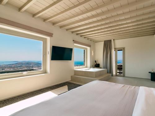 a bedroom with a large bed and a large window at Mykonos Rocks Villas & Suites in Mýkonos City